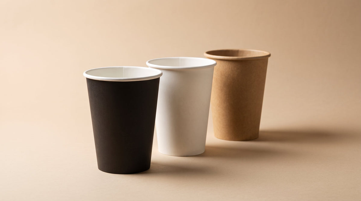 Wholesale single wall paper coffee cups in white, black, and kraft on a cafe counter